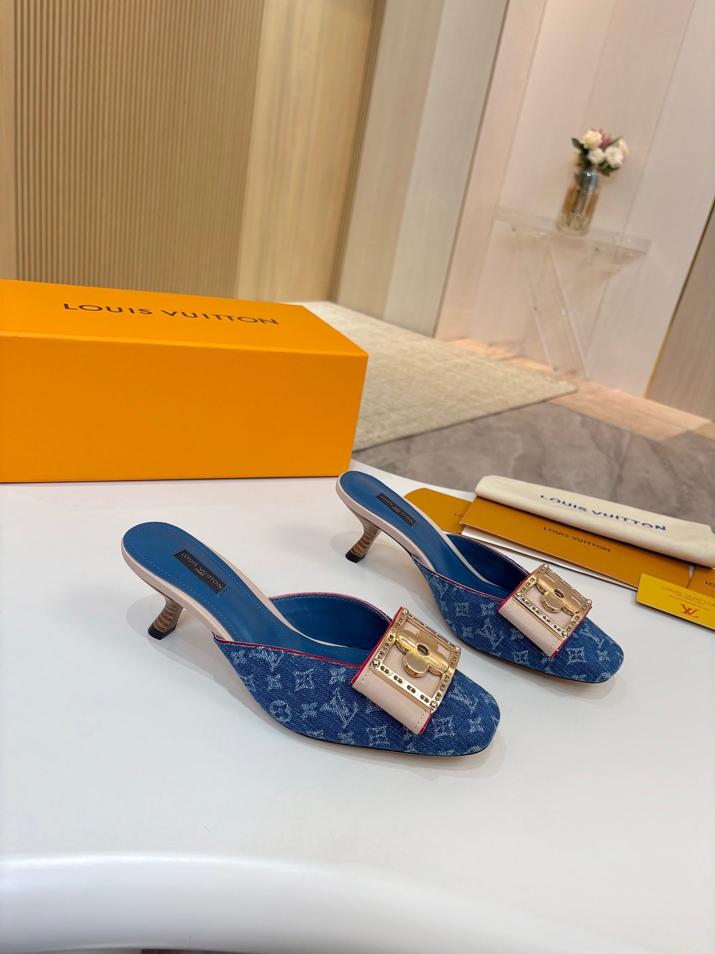 Women's blue monogram mules with gold buckle detail on white display