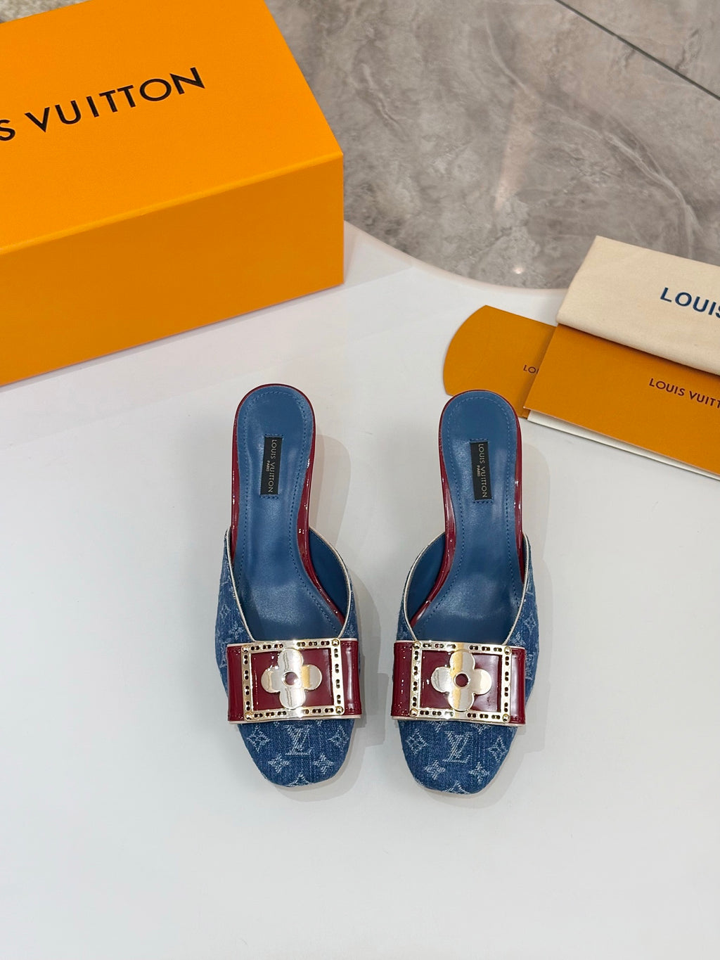Blue monogram slide mules with gold buckle and burgundy trim, front view