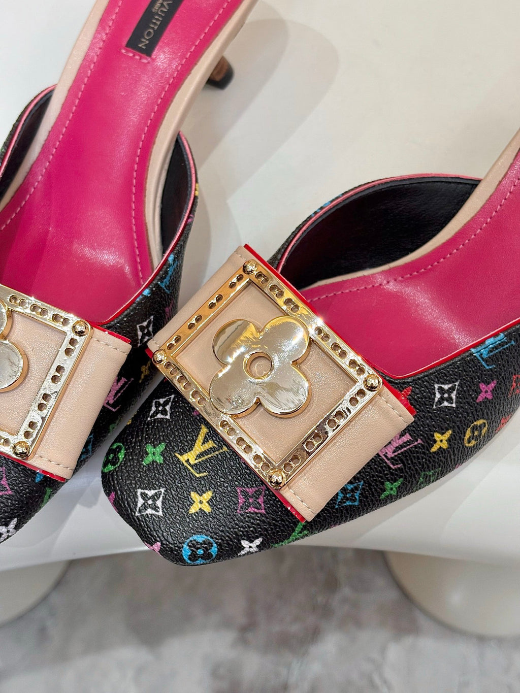 Louis Vuitton ladies shoes close-up: gold emblem buckle on multicolor monogram fabric with pink trim