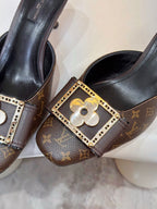 Louis Vuitton mule shoe buckle detail with gold frame and flower emblem on monogram strap