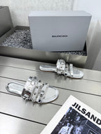 Silver metallic slide sandals with layered straps and shiny buckle hardware
