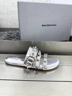 Silver metallic slide sandals with double straps and large buckle hardware