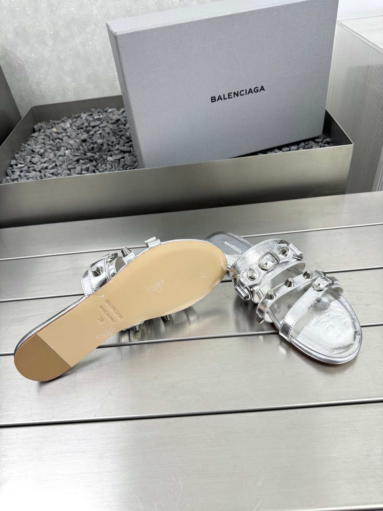 Silver metallic sandals with studded straps and tan outsole visible