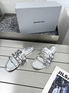 Silver metallic sandals featuring stacked straps and reflective buckle closures