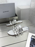 Silver metallic slide sandals with studded straps and buckle details