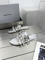 Silver metallic slide sandals with studded straps and buckle details