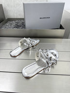 Silver metallic slide sandals with strap buckles and rounded open-toe design