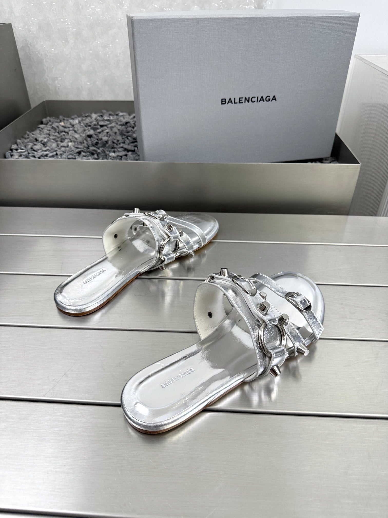 Silver metallic slide sandals with strap buckles and rounded open-toe design