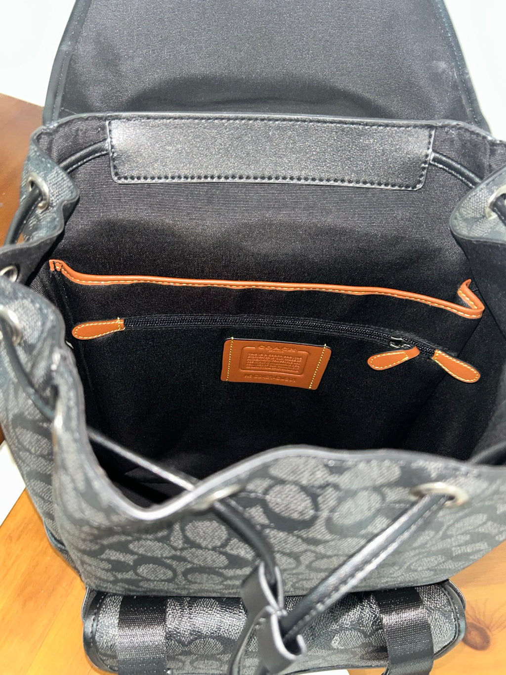 Charcoal monogram backpack interior pocket with orange trim and logo patch