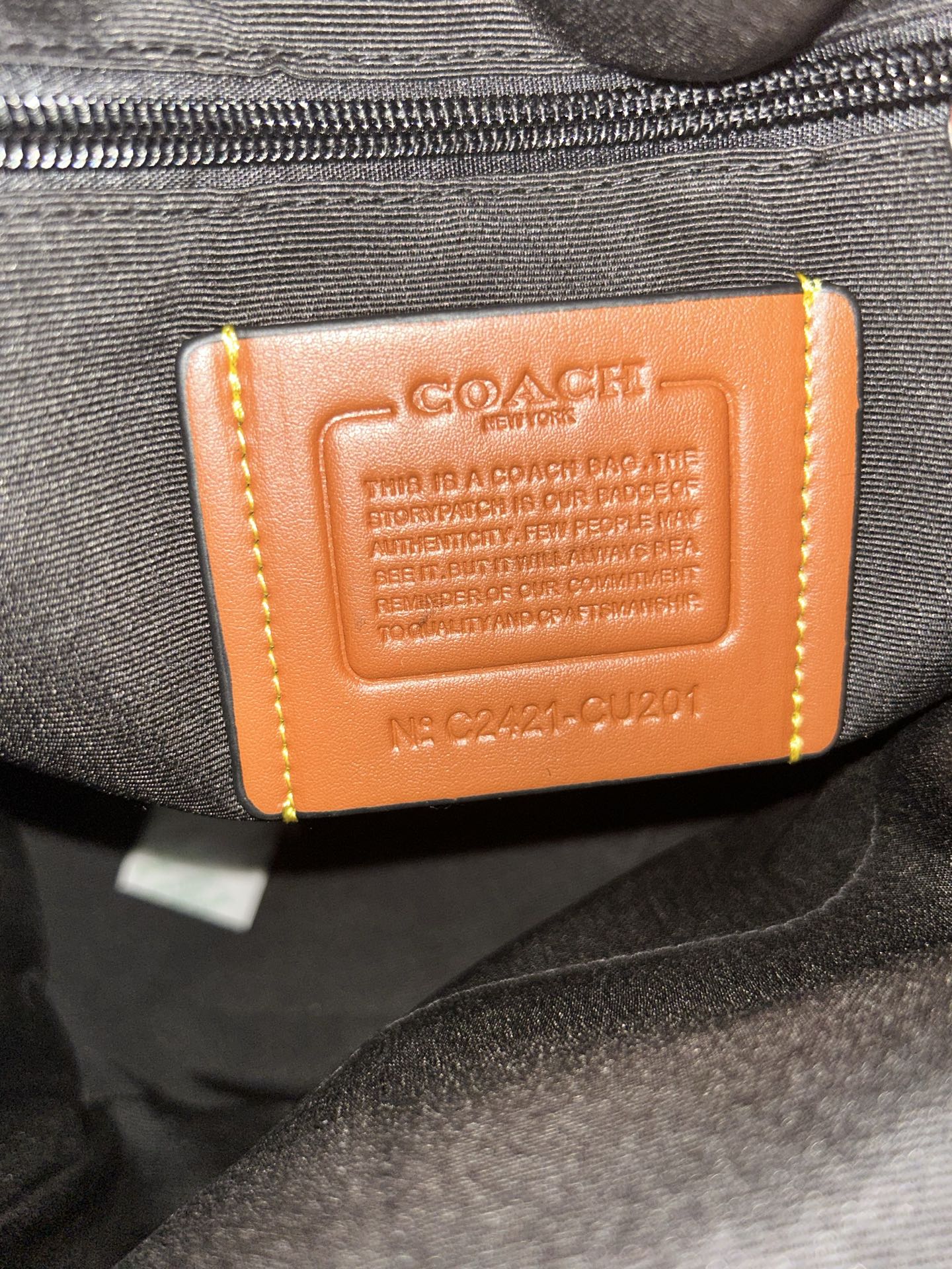 Orange leather logo patch on charcoal backpack zipper area