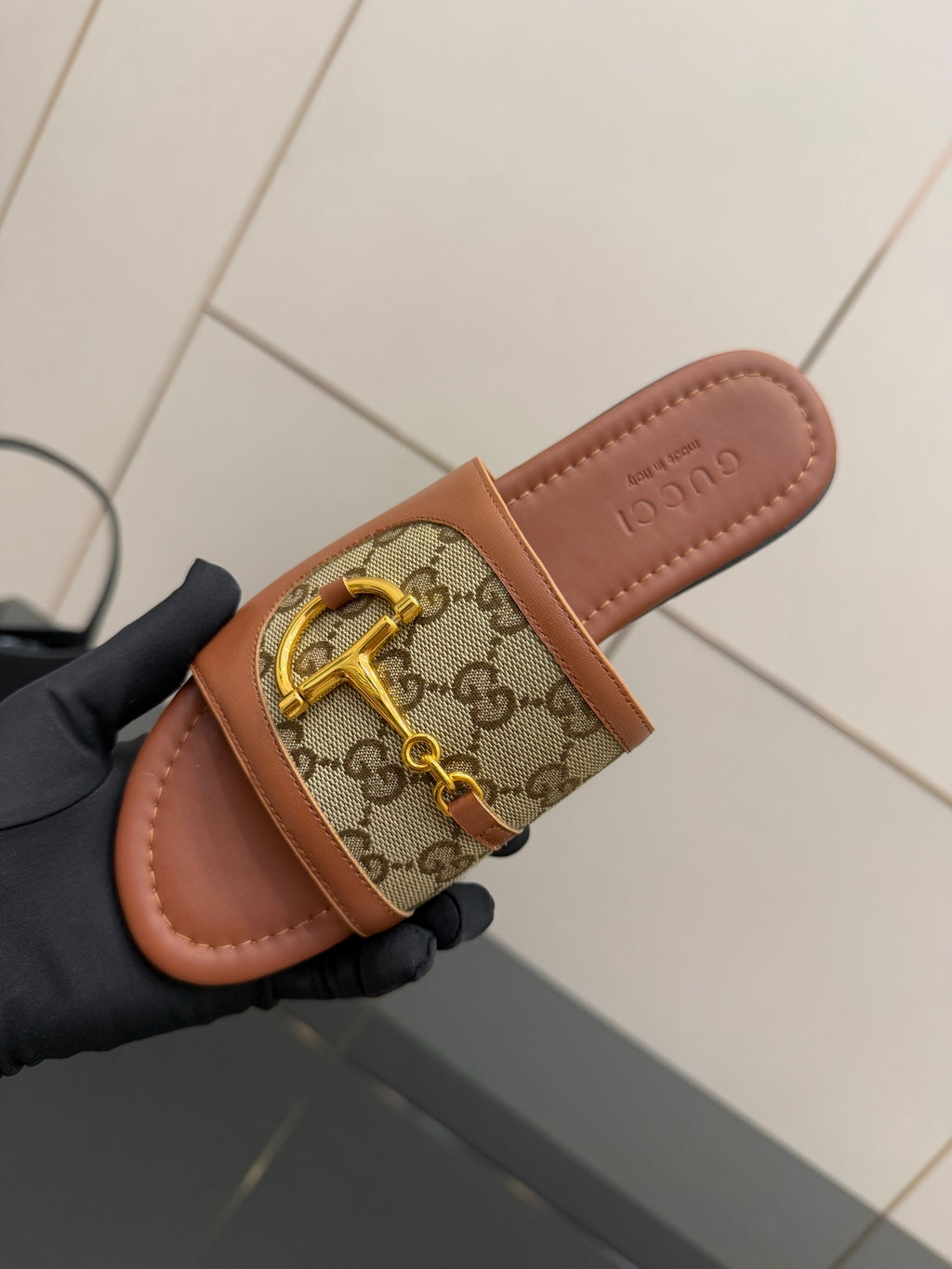 Gucci ladies slide sandal top view, GG canvas band with gold buckle on tan footbed