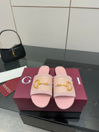 Light pink Gucci slide sandals with gold H-bit strap and open toe, on display box