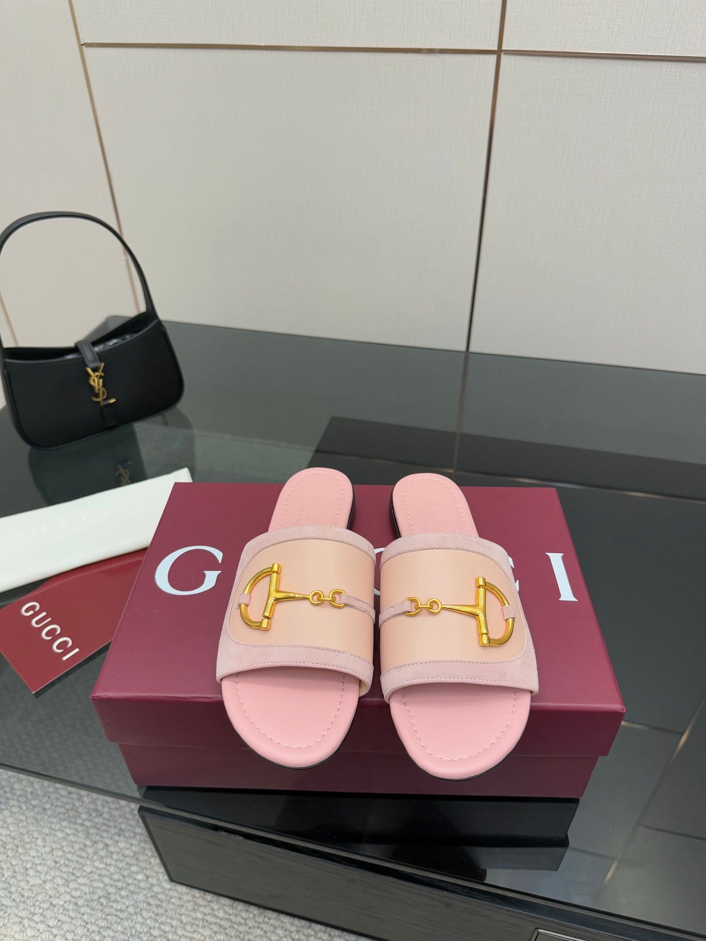 Light pink Gucci slide sandals with gold H-bit strap and open toe, on display box