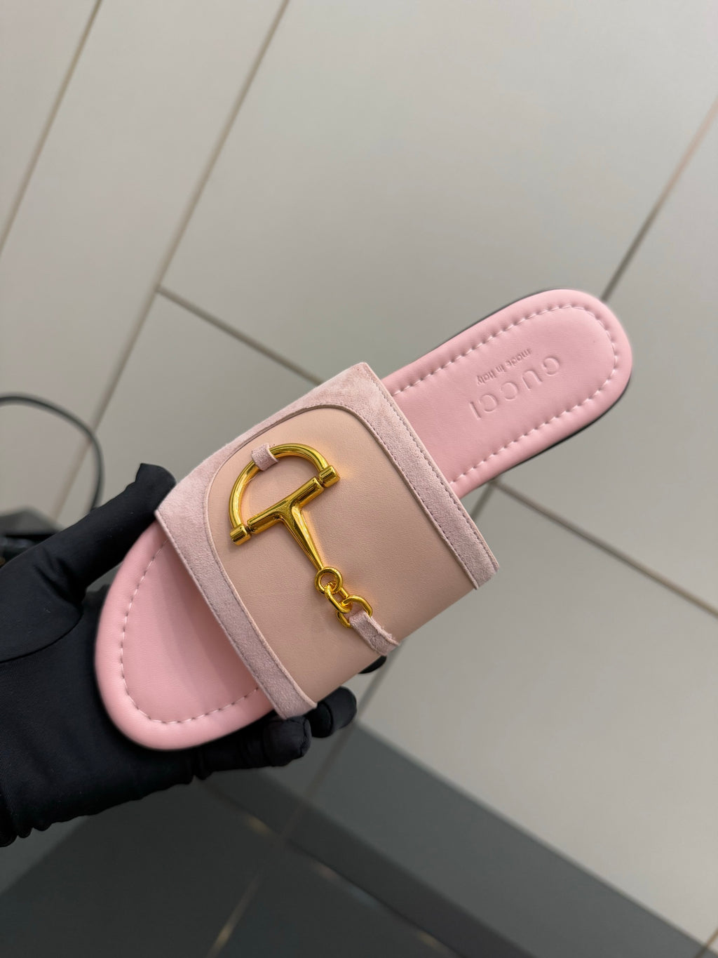 Light pink Gucci slide sandal with gold H-bit strap, footbed close-up