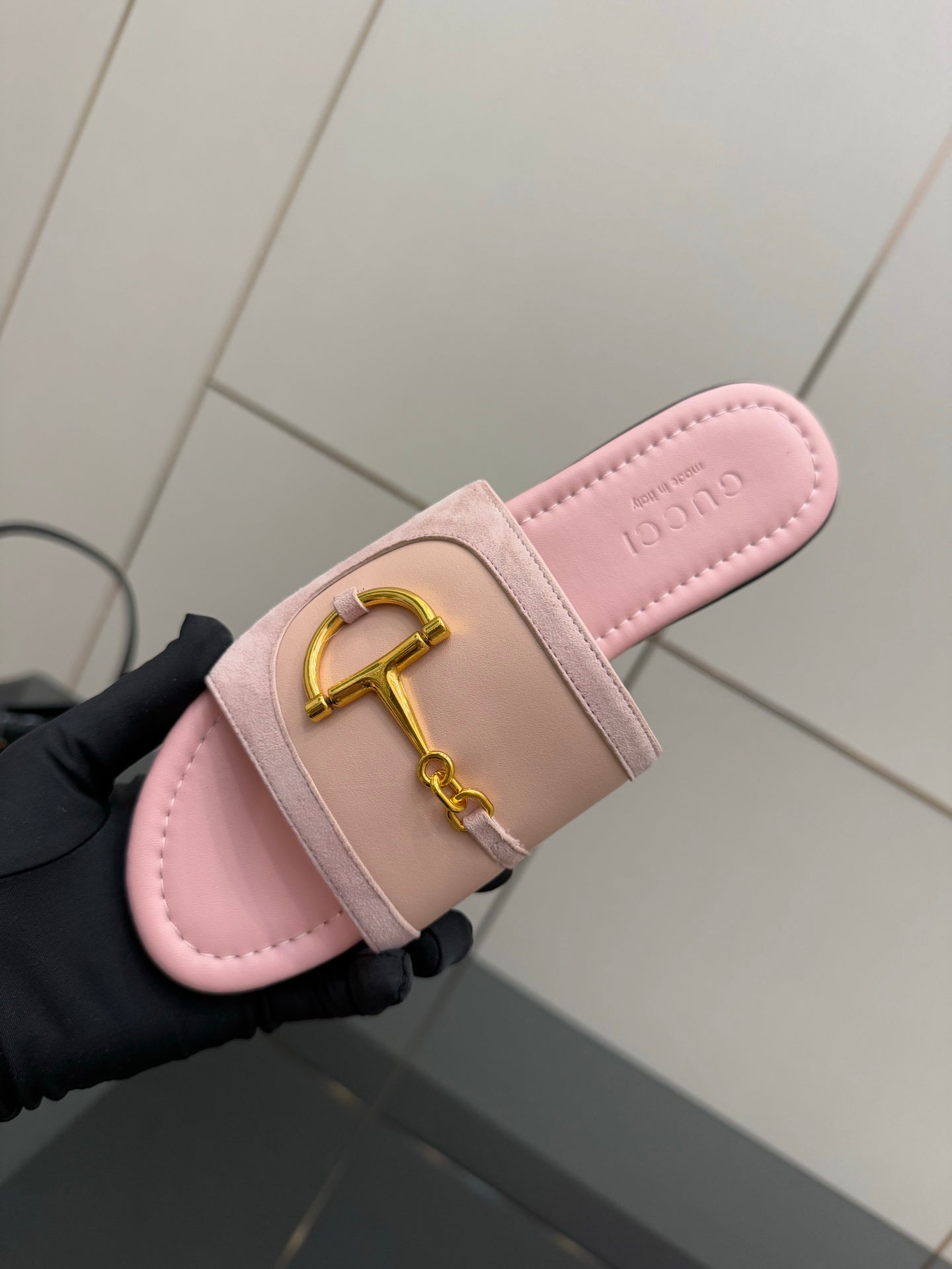 Light pink Gucci slide sandal with gold H-bit strap, footbed close-up