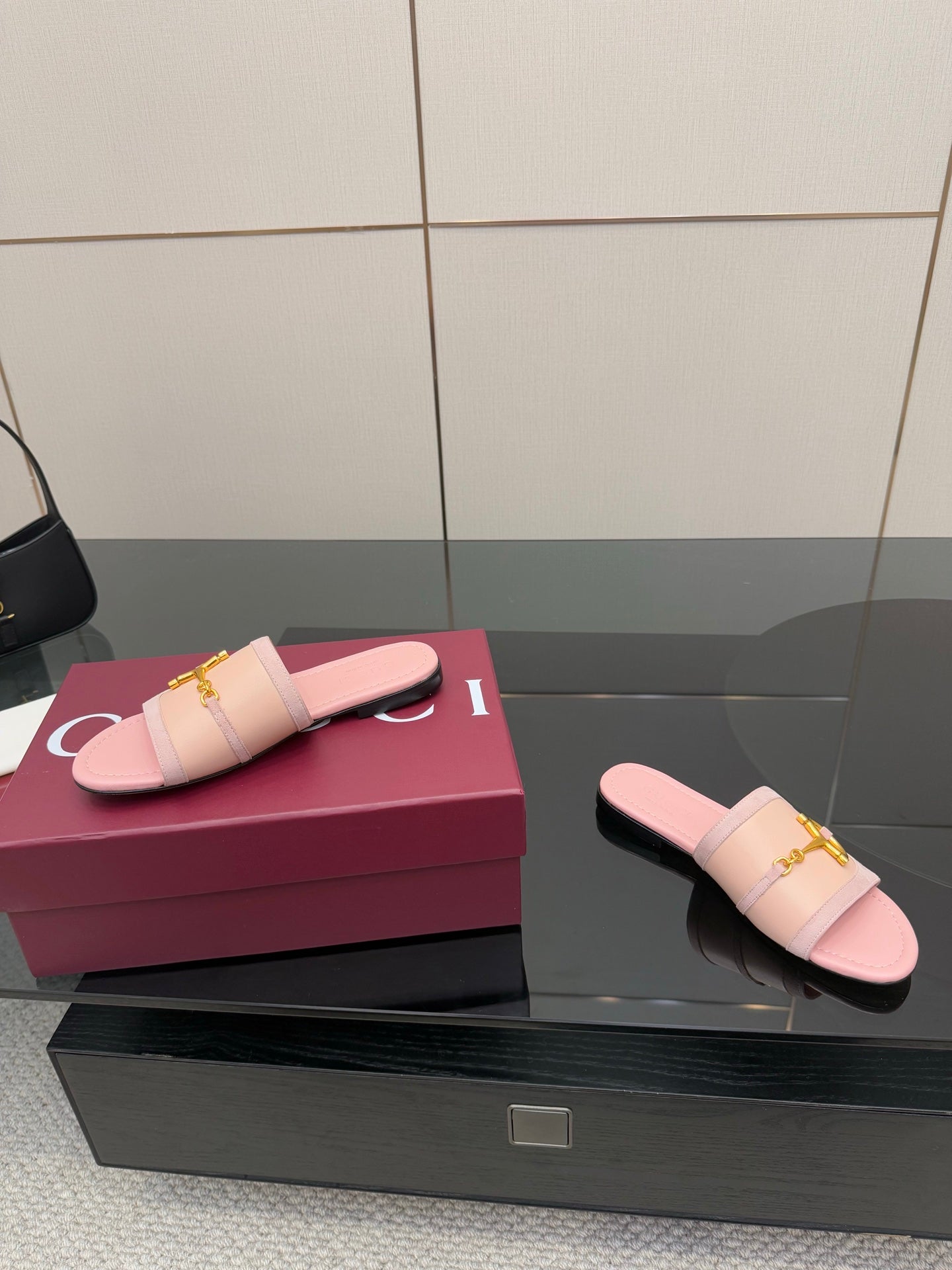 Light pink Gucci slide sandals with gold H-bit hardware, one placed beside the box
