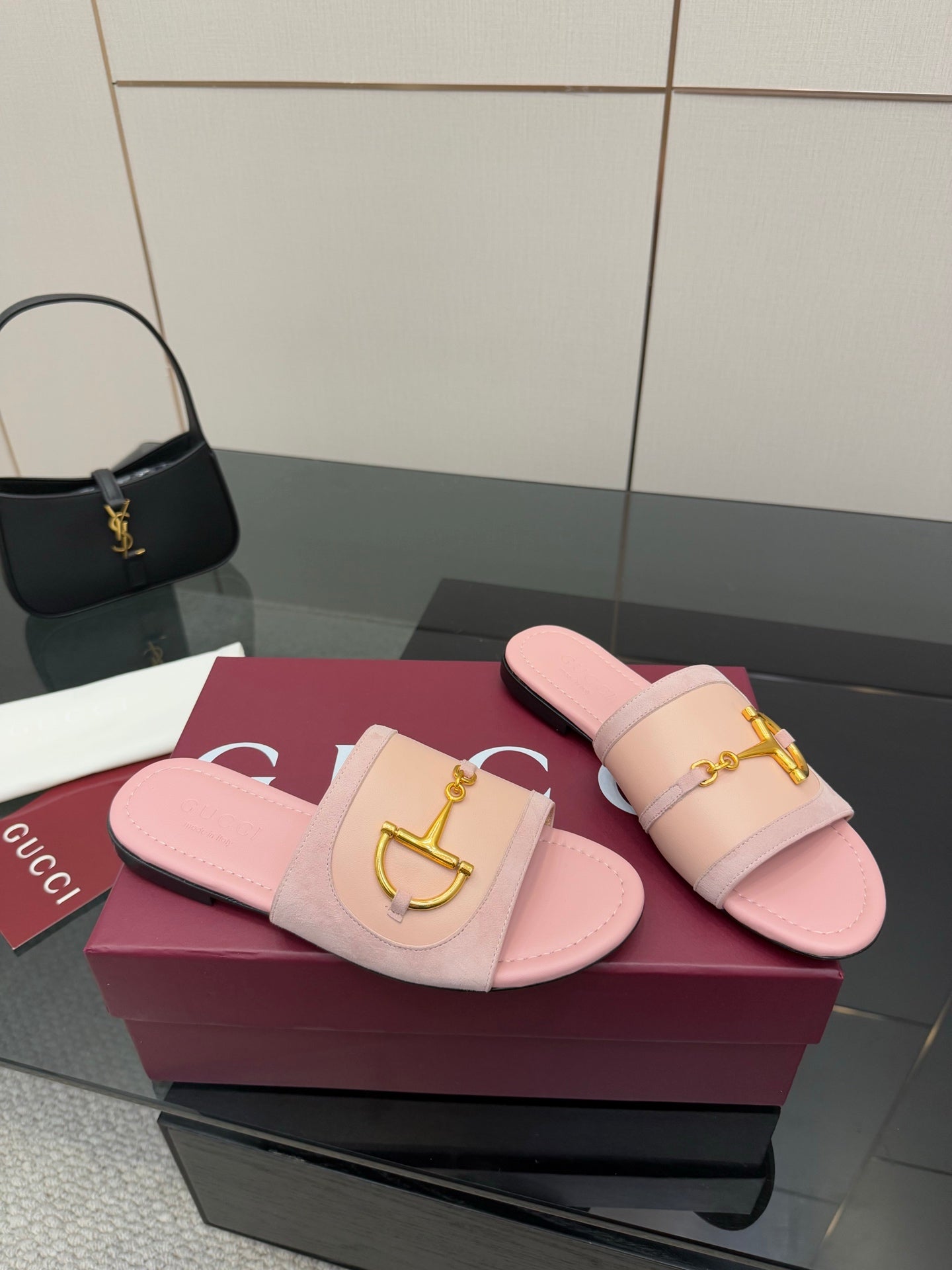 Light pink Gucci slide sandals with gold H-bit strap, side view on display box