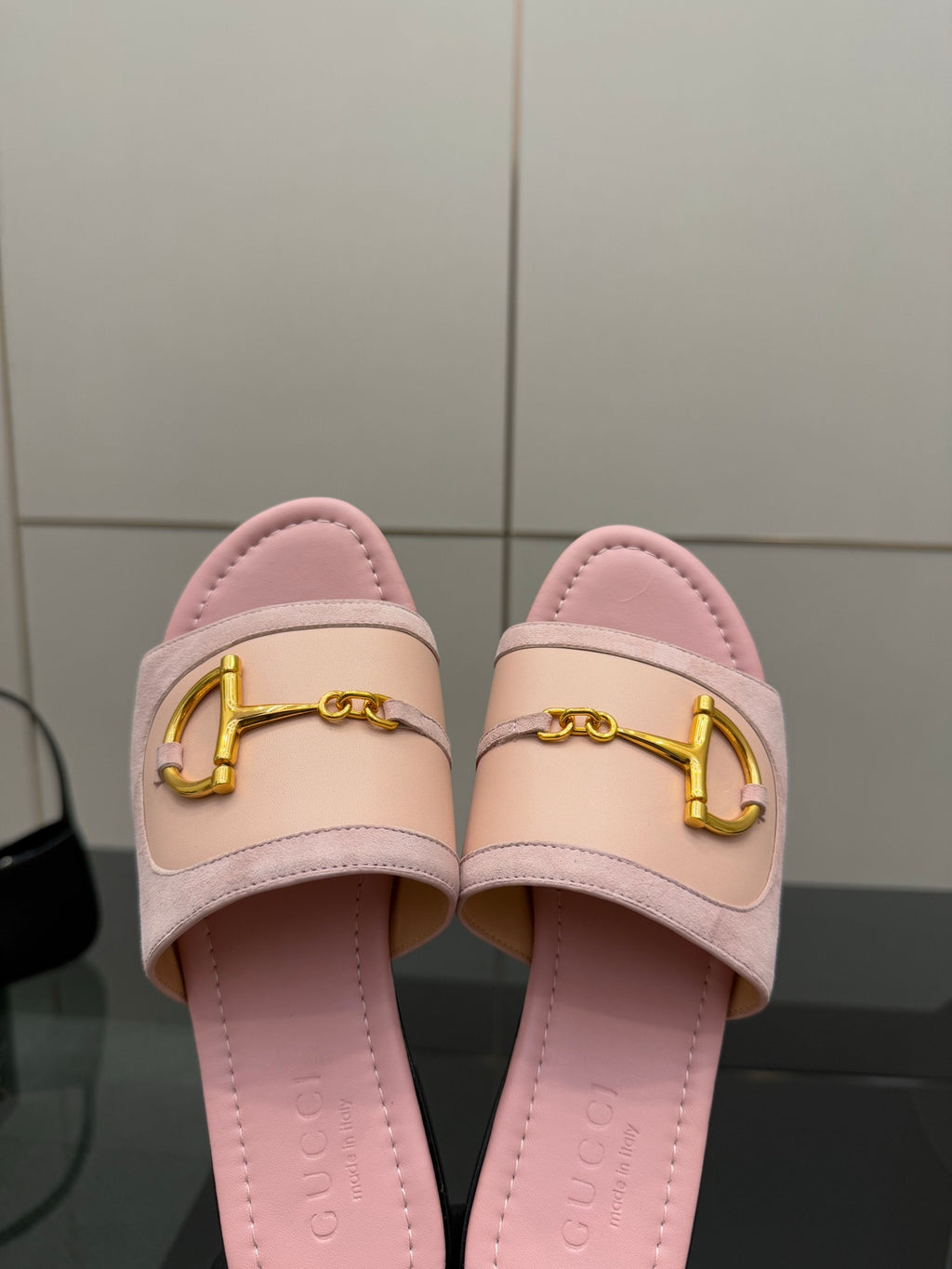 Close-up of light pink Gucci slide sandals with gold H-bit strap and cushioned footbed