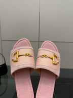 Close-up of light pink Gucci slide sandals with gold H-bit strap and cushioned footbed