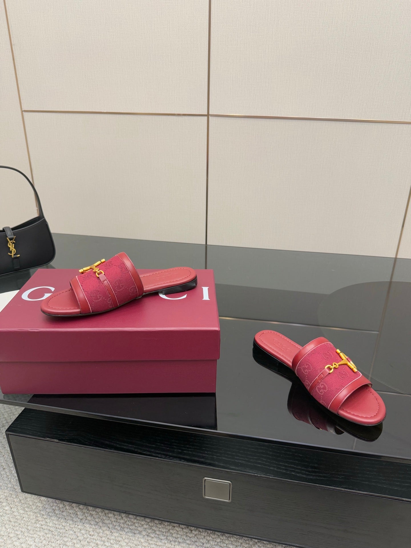 Women’s Gucci slide sandals in dark red leather with gold horsebit detail, angled