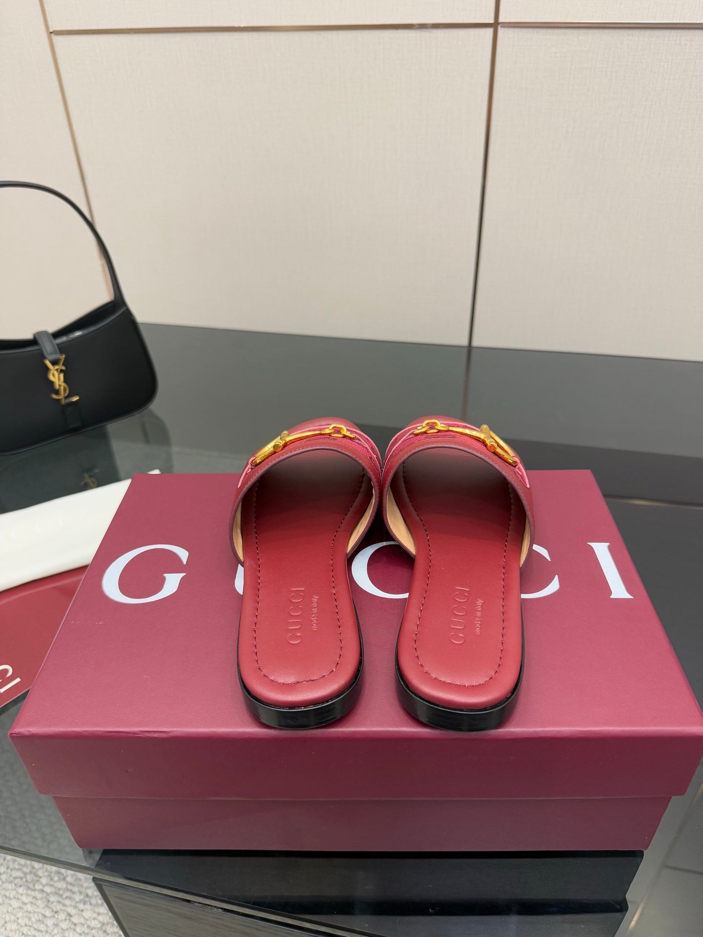Women’s Gucci slide sandals in dark red leather, showing heel openings and strap