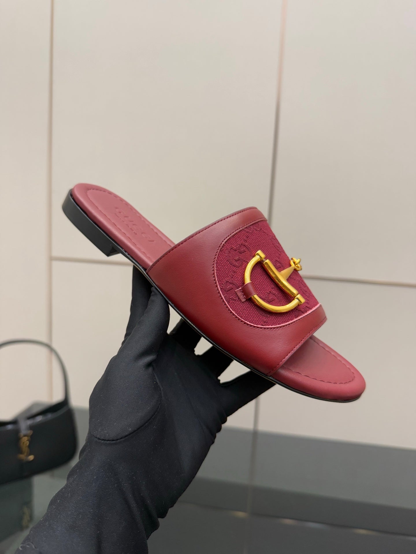 Single women’s Gucci dark red slide sandal in hand with gold horsebit detail