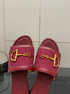 Close-up of women’s Gucci slide sandals in dark red leather with gold horsebit emblem