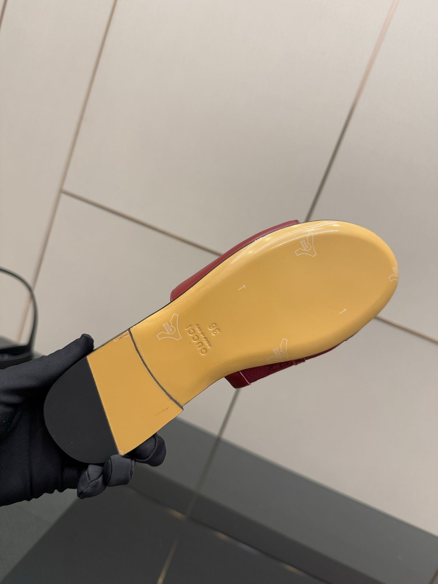 Underside view of women’s Gucci dark red slide sandal with yellow outsole