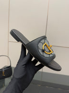 Gucci ladies slide sandal held up, black leather band with gray GG panel and yellow hardware