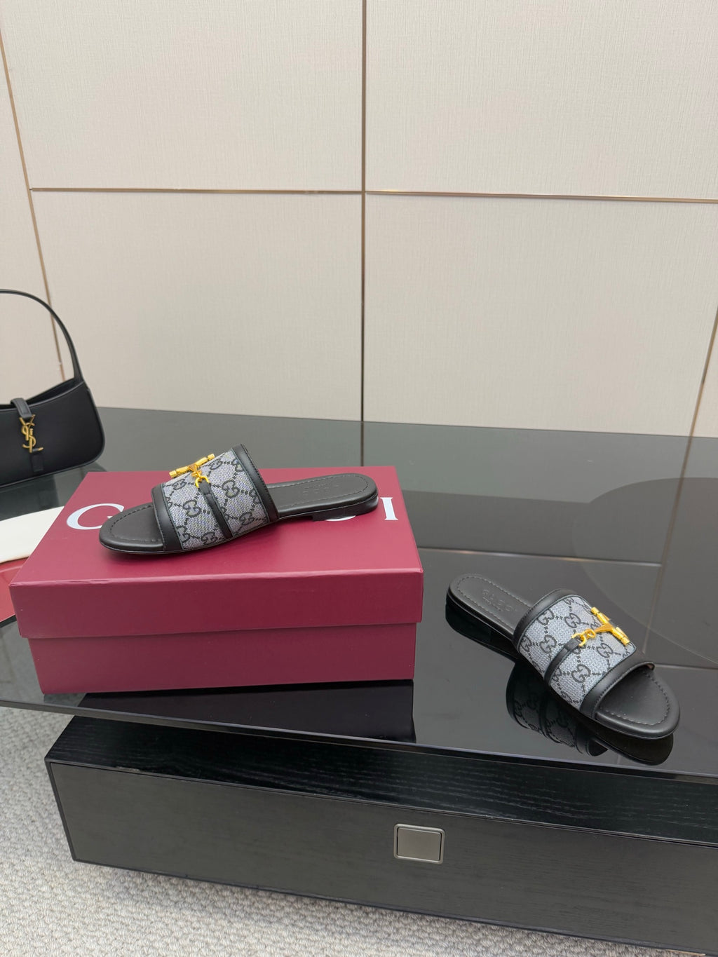 Gucci ladies slide sandals on display, gray GG strap with yellow horsebit detail and black base