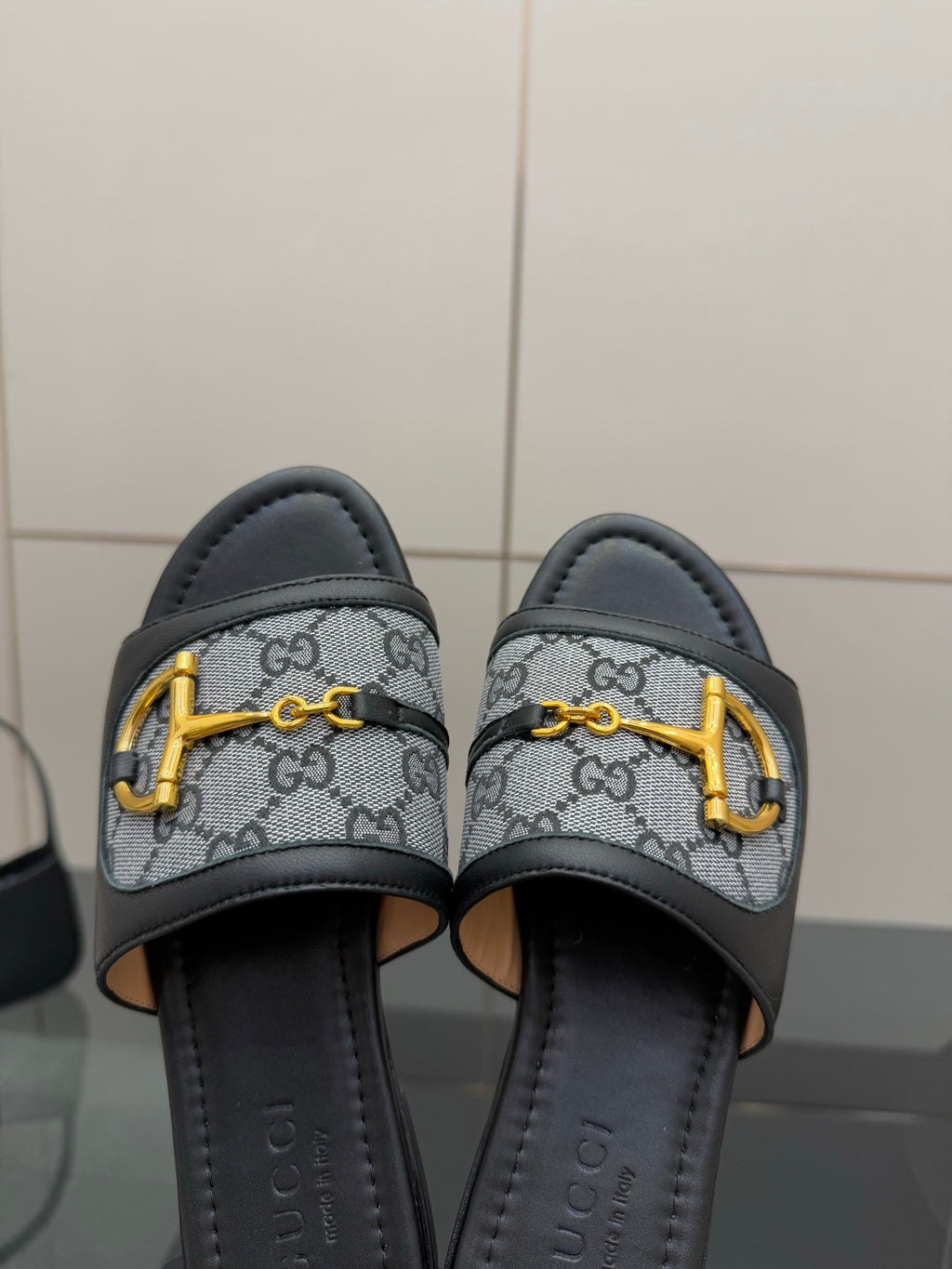 Gucci ladies slide sandals close-up, gray GG canvas straps with yellow hardware and black lining