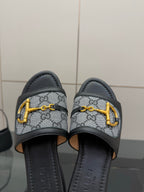 Gucci ladies slide sandals close-up, gray GG canvas straps with yellow hardware and black lining
