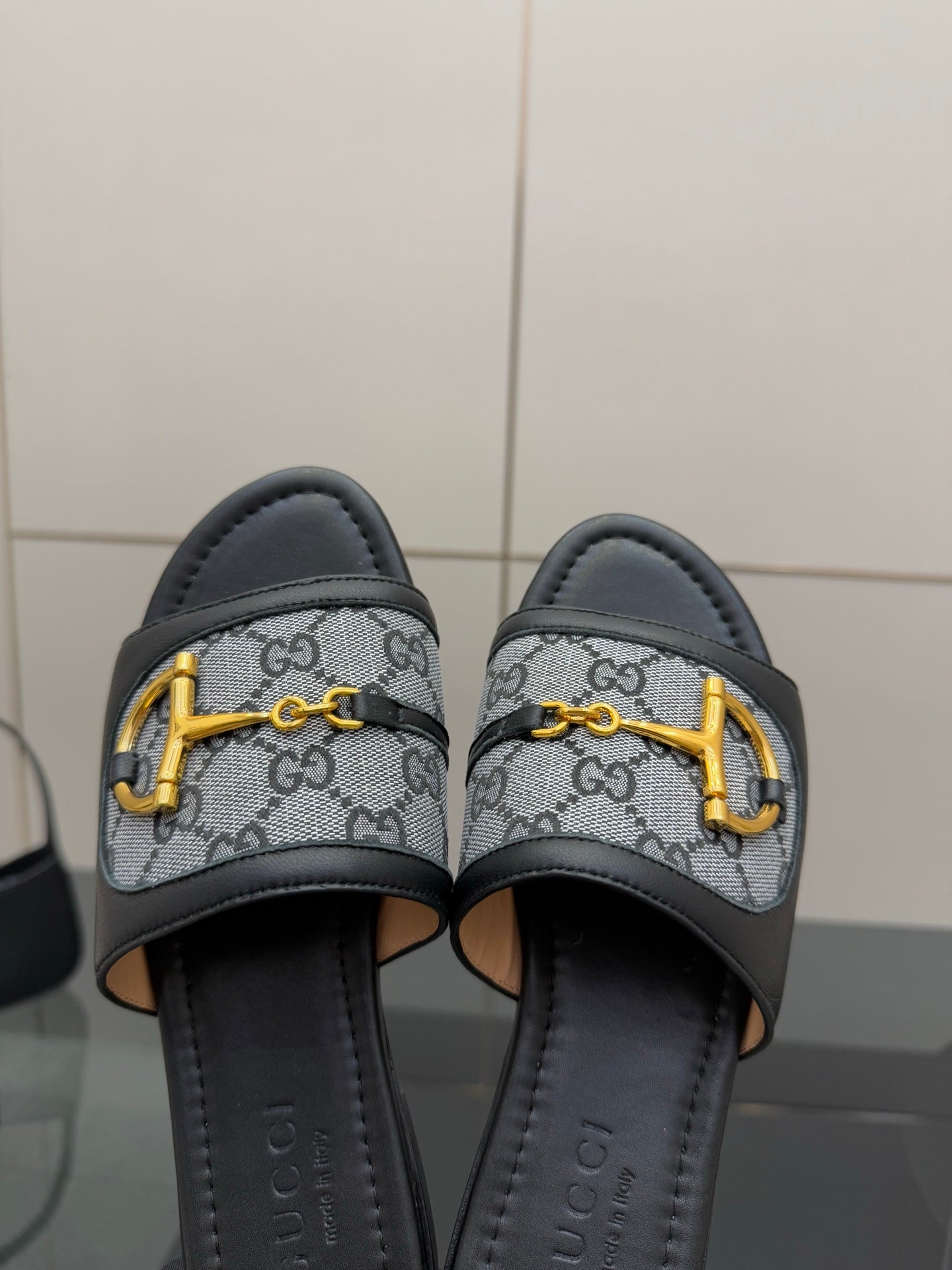 Gucci ladies slide sandals close-up, gray GG canvas straps with yellow hardware and black lining