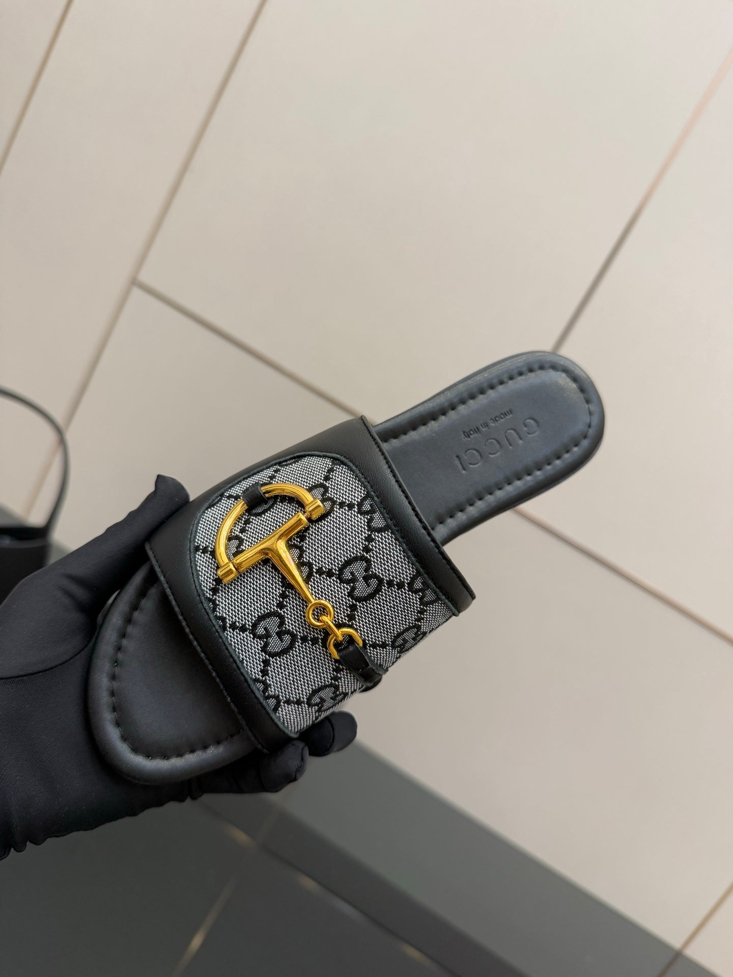 Gucci ladies slide sandal close-up, gray GG canvas strap with yellow logo hardware