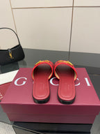 Women's Gucci red slide sandals, front view, with gold-toned hardware and flat sole