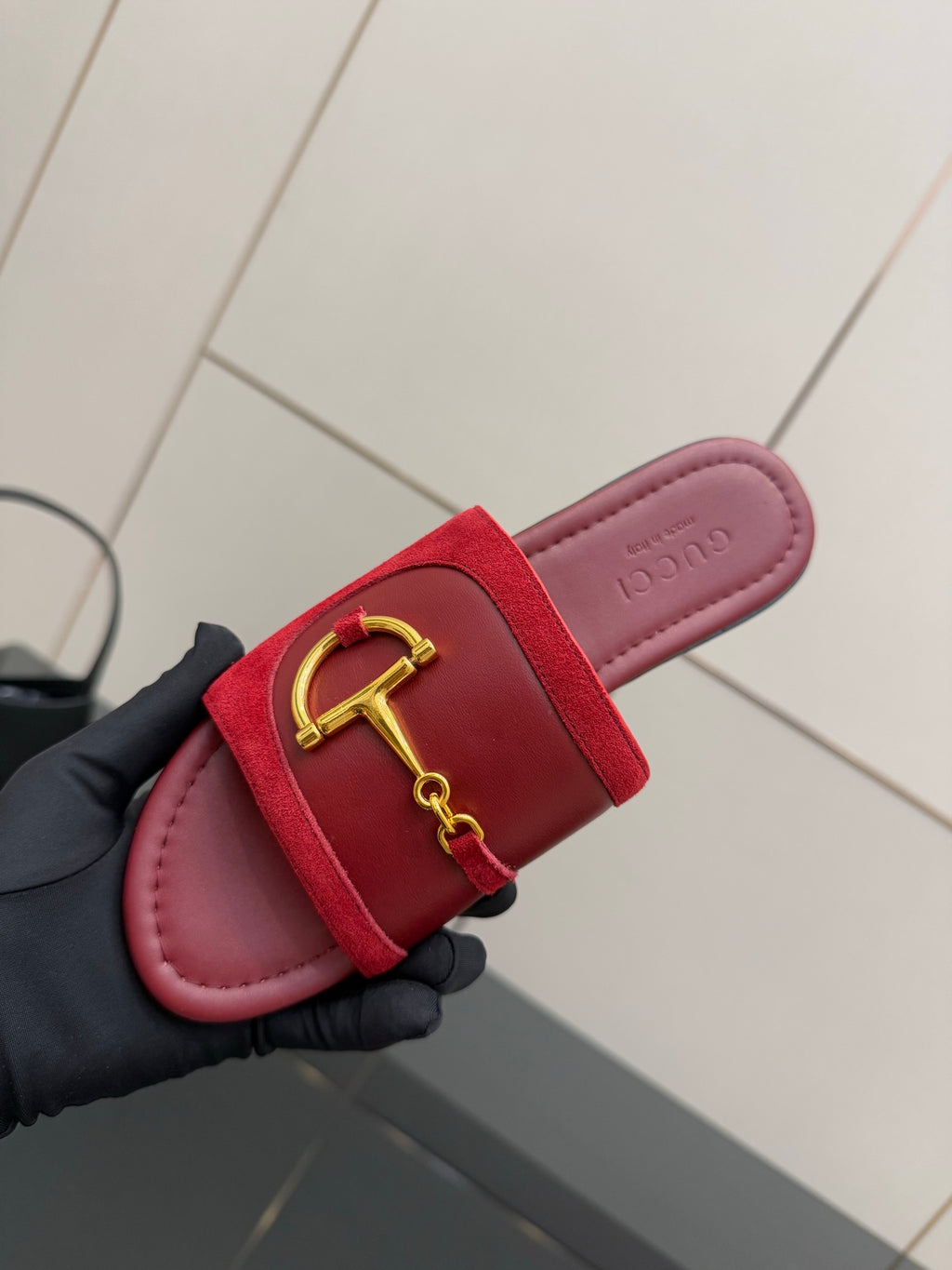 Women's Gucci red slide sandal close-up of gold-toned horsebit strap on footbed