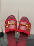 Women's Gucci red slide sandals close-up, gold-toned horsebit hardware on strap