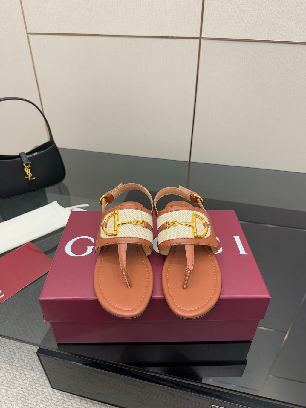 Brown flat thong sandals with white striped straps and gold buckle