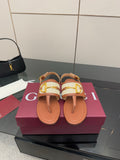 Brown flat thong sandals with white striped straps and gold buckle