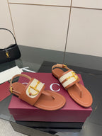 Tan flat thong sandals with white striped upper and gold buckle, side view