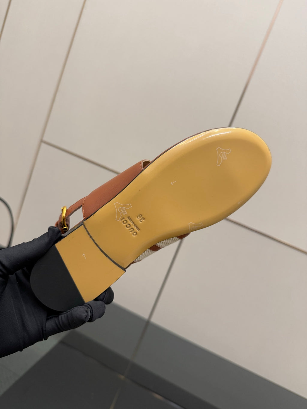 Tan sandal outsole with embossed branding, flat sole underside view