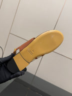 Tan sandal outsole with embossed branding, flat sole underside view