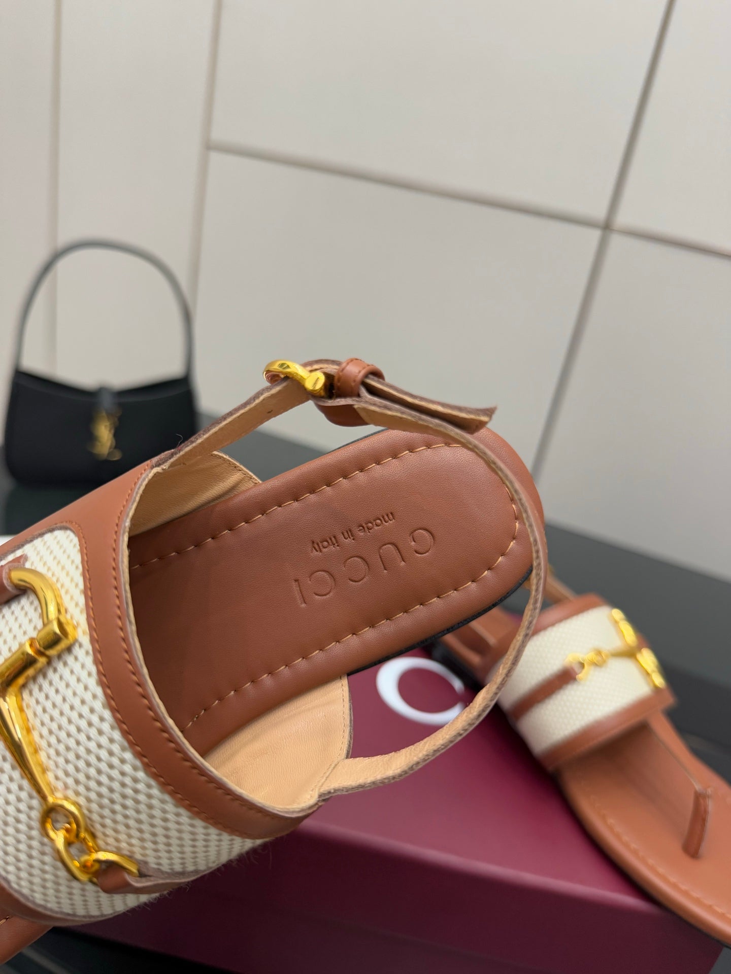 Tan thong sandals with white striped strap and gold buckle, Gucci insole close-up