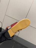 Red slide sandal outsole shown with tan rubber sole and gold buckle strap