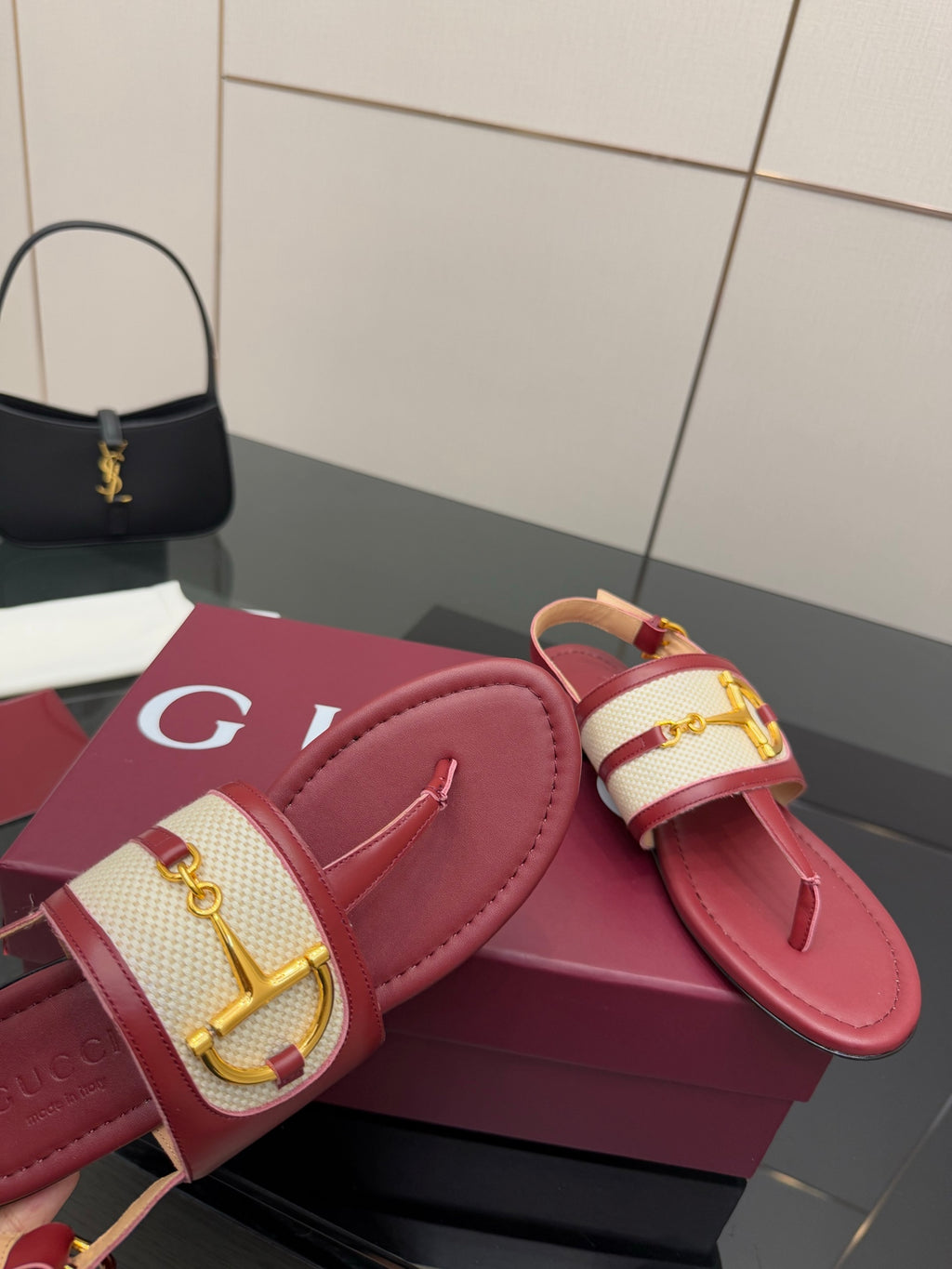 Red slide sandals with gold buckle detail on patterned strap