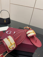 Red slide sandals with gold buckle detail on patterned strap