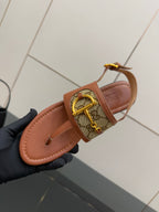 Gucci thong sandal close-up, tan footbed with patterned strap and gold buckle