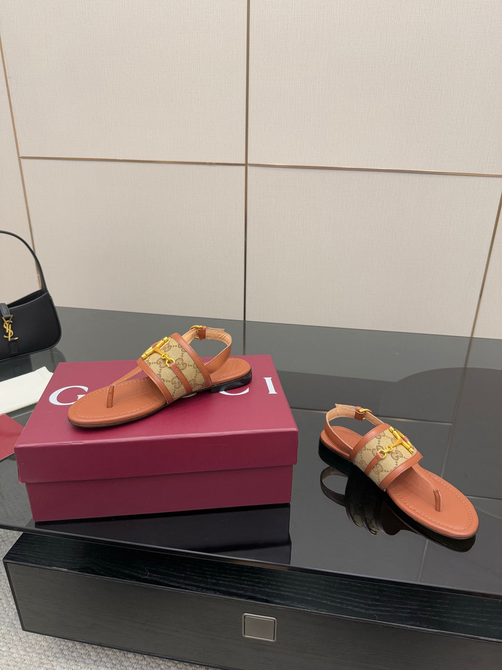 Pair of Gucci thong sandals with tan leather-look straps and gold hardware on footbed