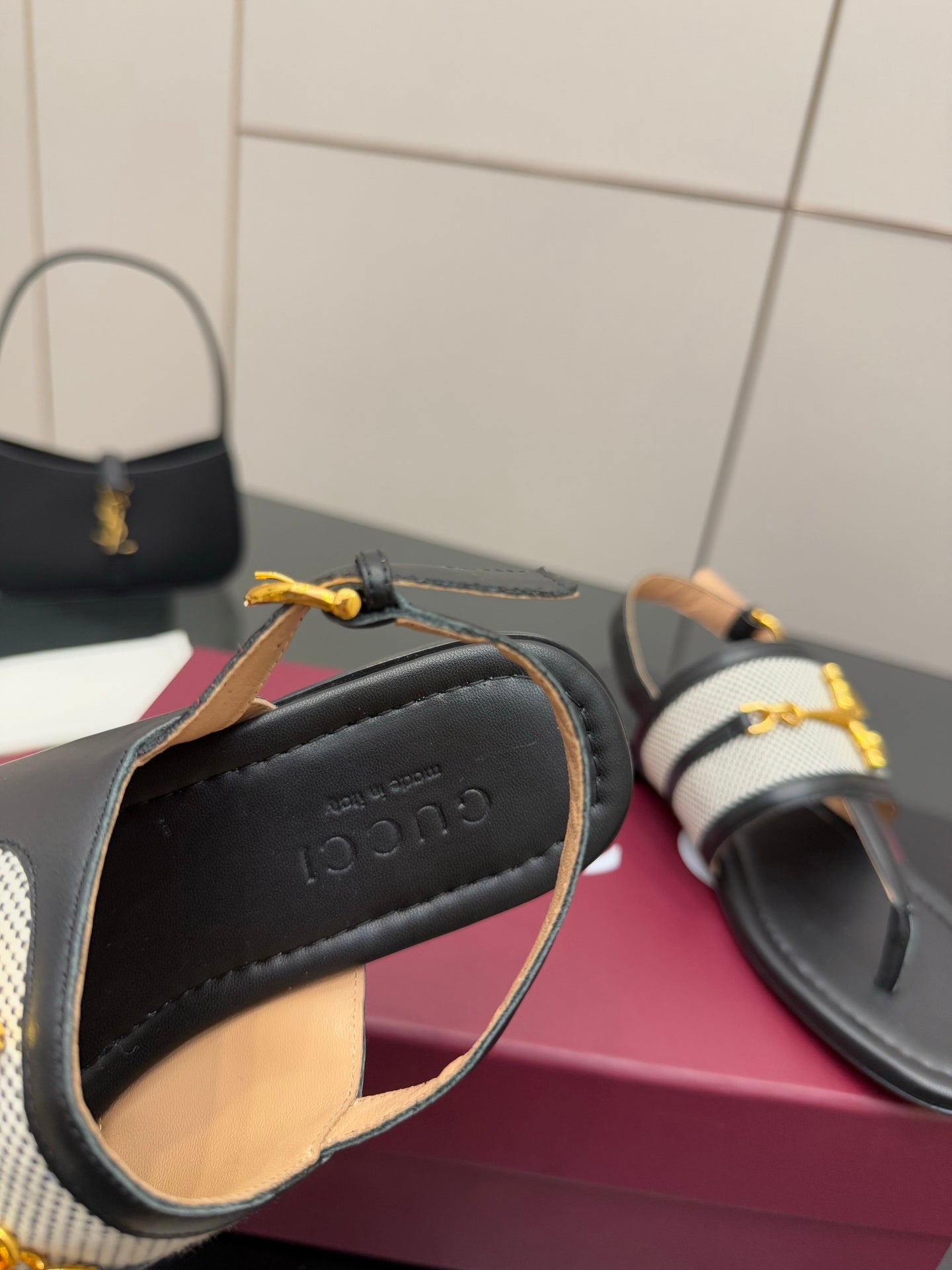 Ladies slide sandal close-up: black lining, tan trim, gold buckle on white check fabric