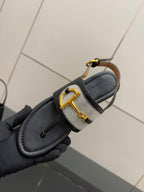 Ladies slide sandal close-up: black outsole with white check strap band and gold buckle